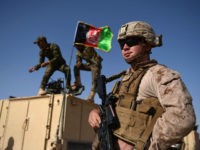 In this photograph taken on August 28, 2017, a US Marine looks on as Afghan National Army soldiers raise the Afghan National flag on an armed vehicle during a training exercise to deal with IEDs (improvised explosive devices) at the Shorab Military Camp in Lashkar Gah in Helmand province. Marines in Afghanistan's Helmand say Donald Trump's decision to keep boots on the ground indefinitely gives them 'all the time in the world' to retake the province, once the symbol of US intervention but now a Taliban stronghold. They may need it. At the hot, dusty Camp Shorab, where many of the recently deployed Marines train their Afghan counterparts in flat, desert terrain, the Afghans admit their army still cannot fight alone. / AFP PHOTO / WAKIL KOHSAR (Photo credit should read WAKIL KOHSAR/AFP/Getty Images)