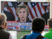 People walking at Ronald Reagan National Airport airport gather around a television monitor and watch US Democratic nominee Hillary Clinton deliver her concession speech November 9, 2016, a day following the election that US Republican nominee Donald Trump won in Arlington, Virginia. / AFP / PAUL J. RICHARDS (Photo credit should read PAUL J. RICHARDS/AFP/Getty Images)