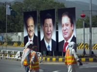 In this April 20, 2015 file photo, municipality workers walk past a billboard showing pictures of Chinese President Xi Jinping, center, with Pakistan's President Mamnoon Hussain, left, and Prime Minister Nawaz Sharif on display during a two-day visit by the Chinese president to launch an ambitious $45 billion economic corridor linking Pakistan's port city of Gwadar with western China, in Islamabad, Pakistan. China's new Silk Road initiative is ramping up as President Donald Trump focuses on domestic